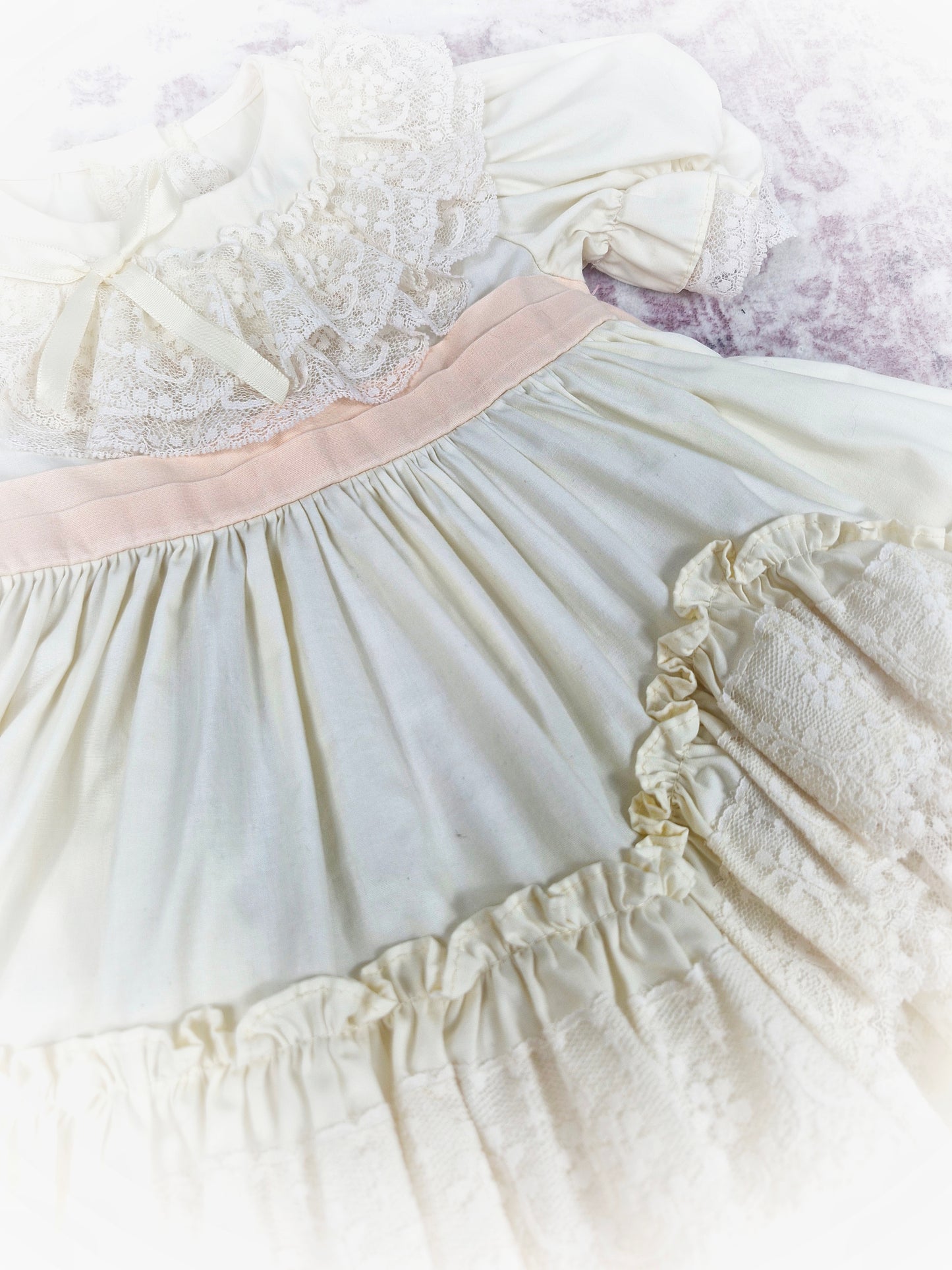 9-12 months. Cream vintage dress with lace, frills and layers and a peach tieback
