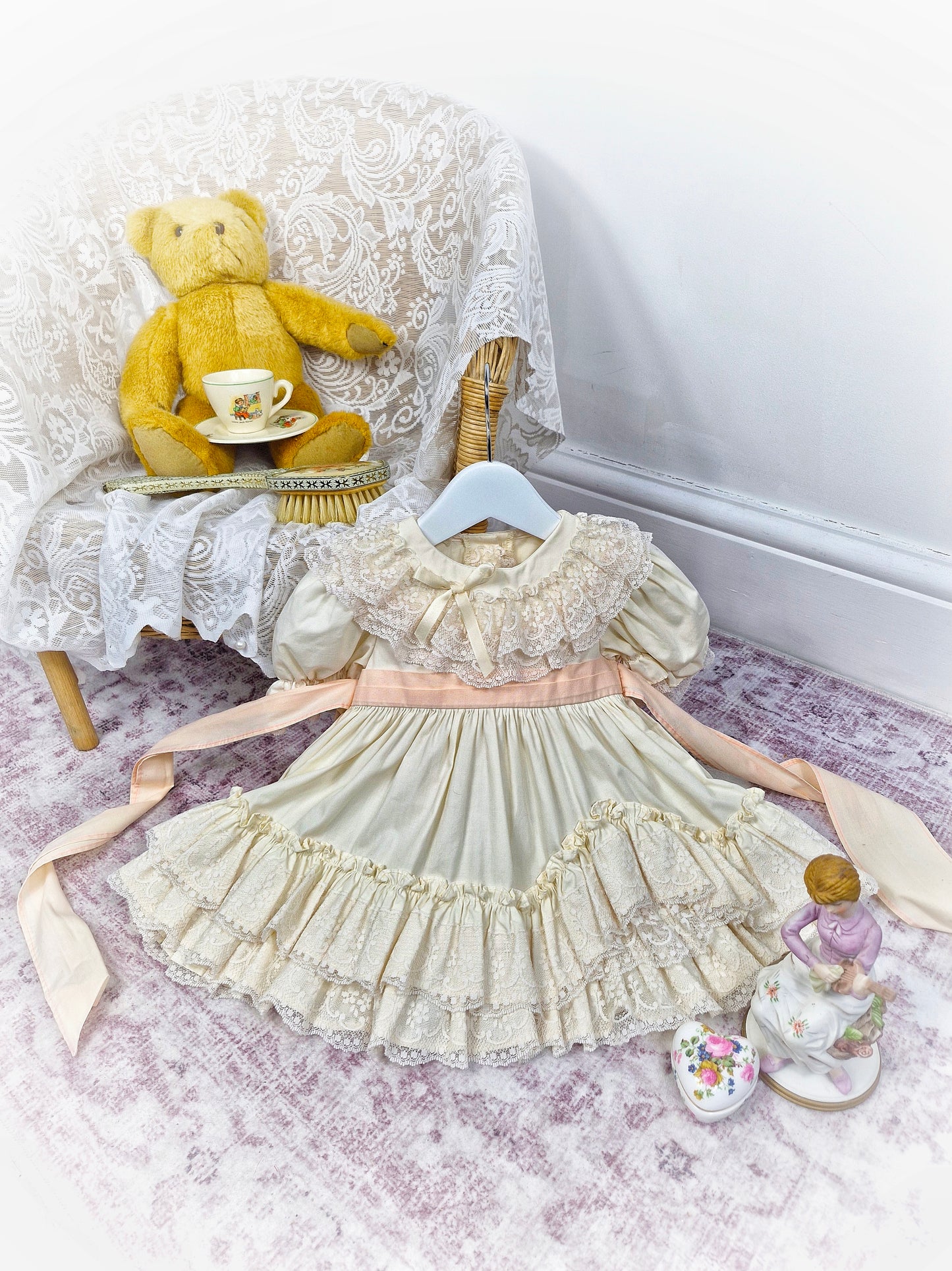9-12 months. Cream vintage dress with lace, frills and layers and a peach tieback