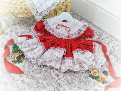 6-12 months. Red Lid'l Dolly with white bib and lace ruffles
