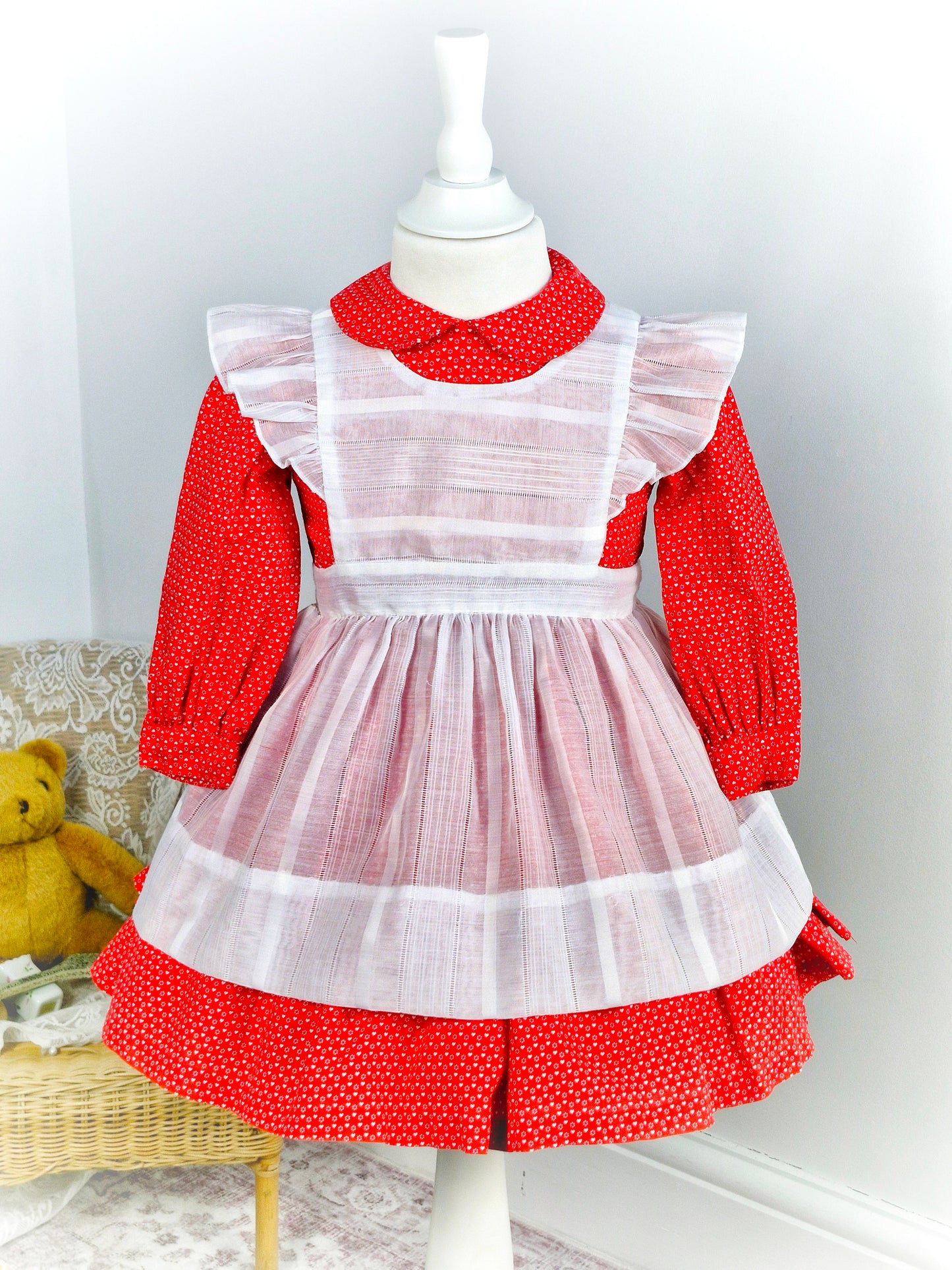 2-3 years. Handmade two-piece, red long sleeve dress with Peter Pan collar and white heart print. White apron with flutter shoulders and tie back.