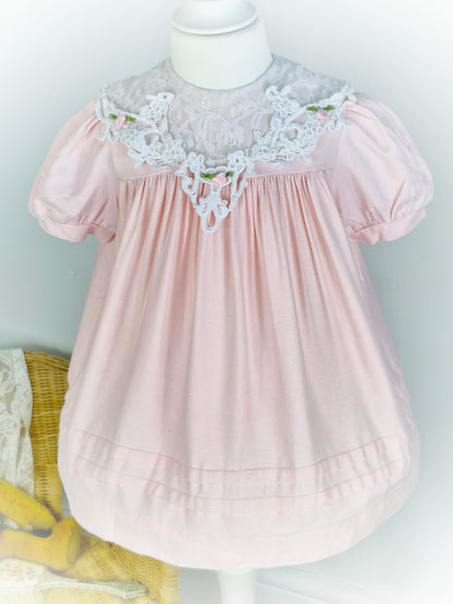 2 years. Light pink vintage dress with elegant lace bib and rosettes