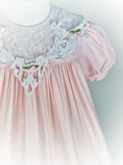 2 years. Light pink vintage dress with elegant lace bib and rosettes