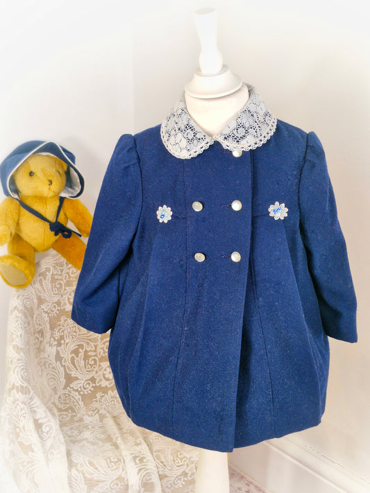 2 years. Navy double breasted coat and bonnet set with with lace details, flowers and button by Cute Togs. Small dot on collar*