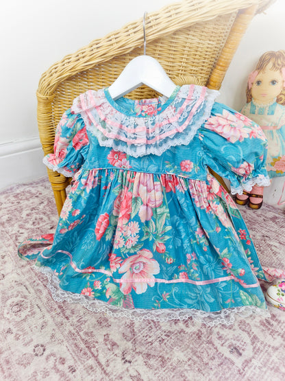 18-24 months. Teal vintage dress by Petit Amour, pink ribbon and flowers with white lace and puff sleeves