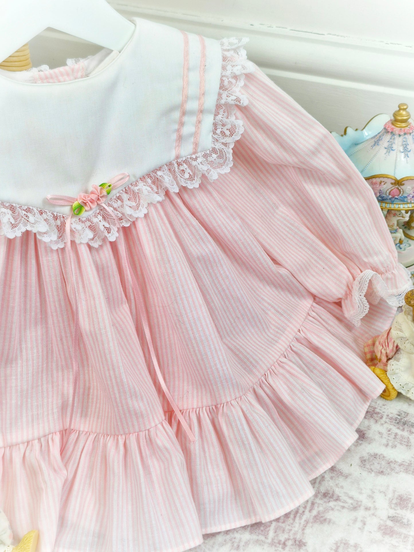 9-12 months. White and pink candy striped Bryan, white bib with lace trim, pink ribbon and rosette