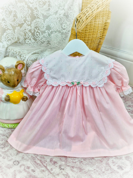 9-12 months. Pink vintage Bryan with white eyelet bib, pink ribbon and puff sleeves
