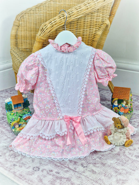12-18 months. Pink and white vintage floral drop waist dress with frill neck and pink satin ribbon