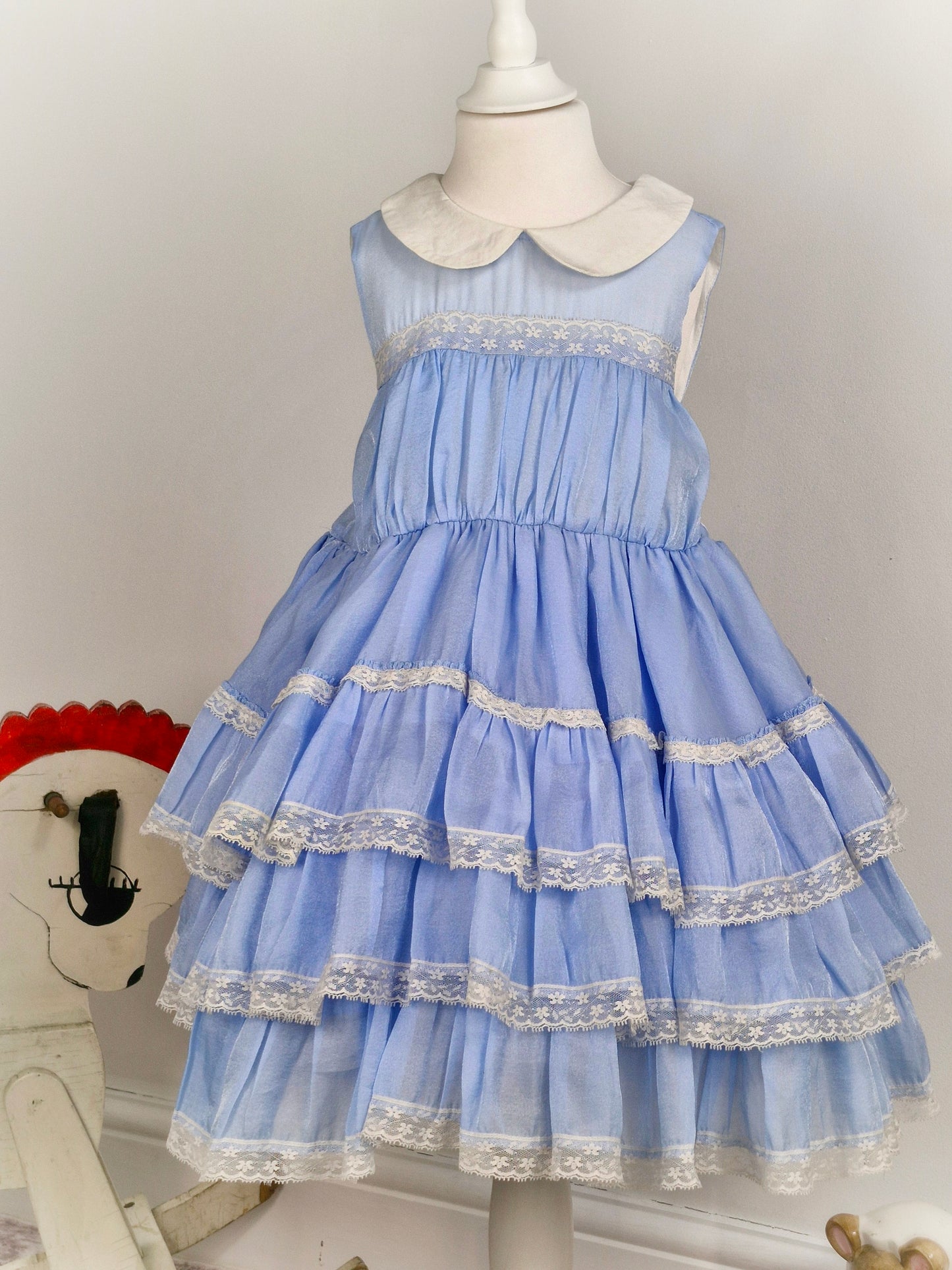 6 years. Light blue sleeveless dress with white collar, lace trim and ruffled layers