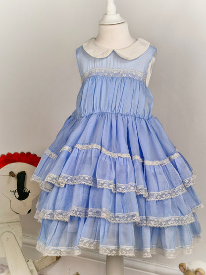 6 years. Light blue sleeveless dress with white collar, lace trim and ruffled layers
