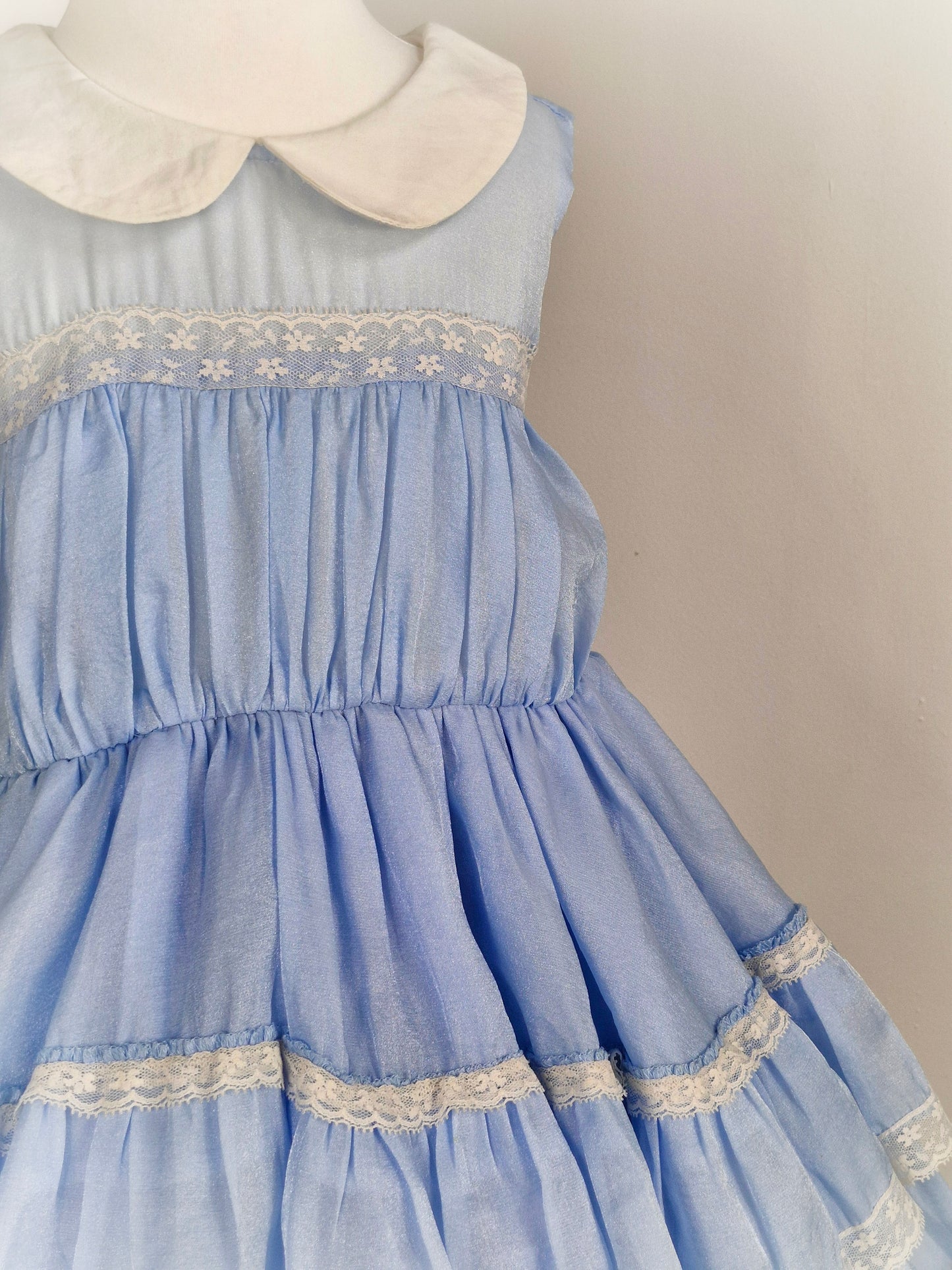 6 years. Light blue sleeveless dress with white collar, lace trim and ruffled layers