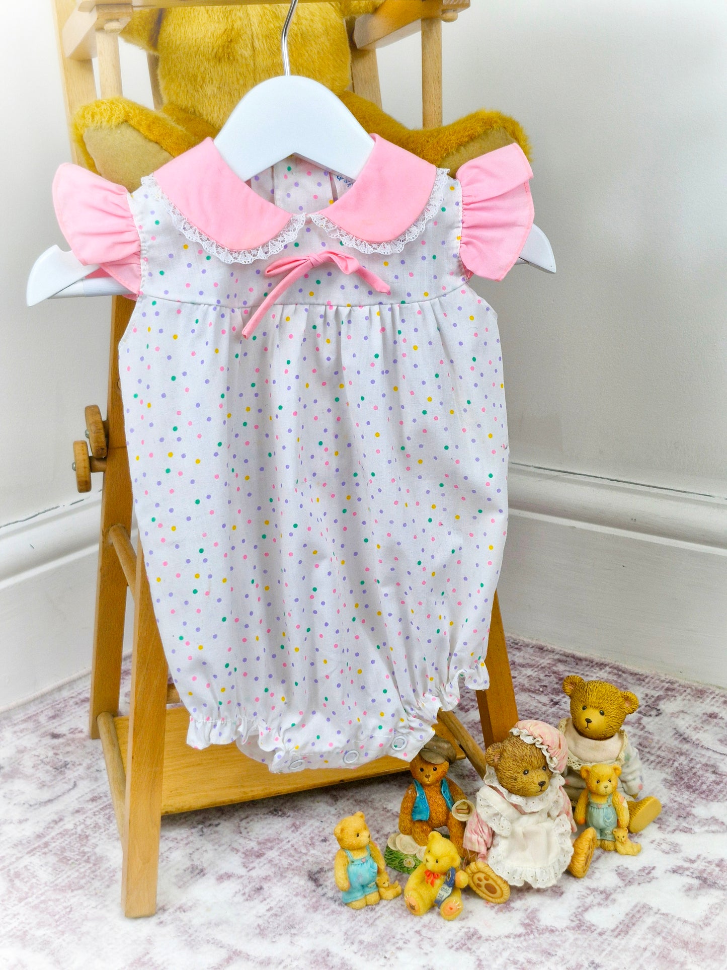 9-12 months. White vintage romper with pink collar, flutter shoulders and rainbow polka dots