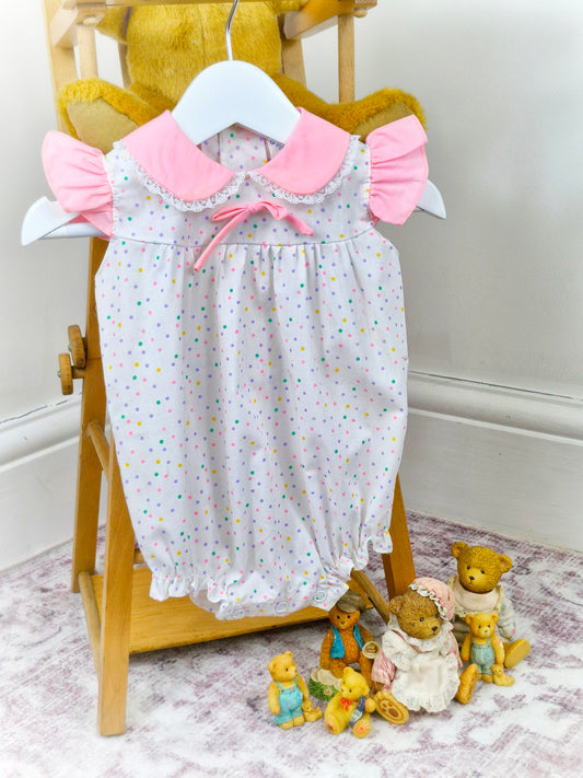 9-12 months. White vintage romper with pink collar, flutter shoulders and rainbow polka dots