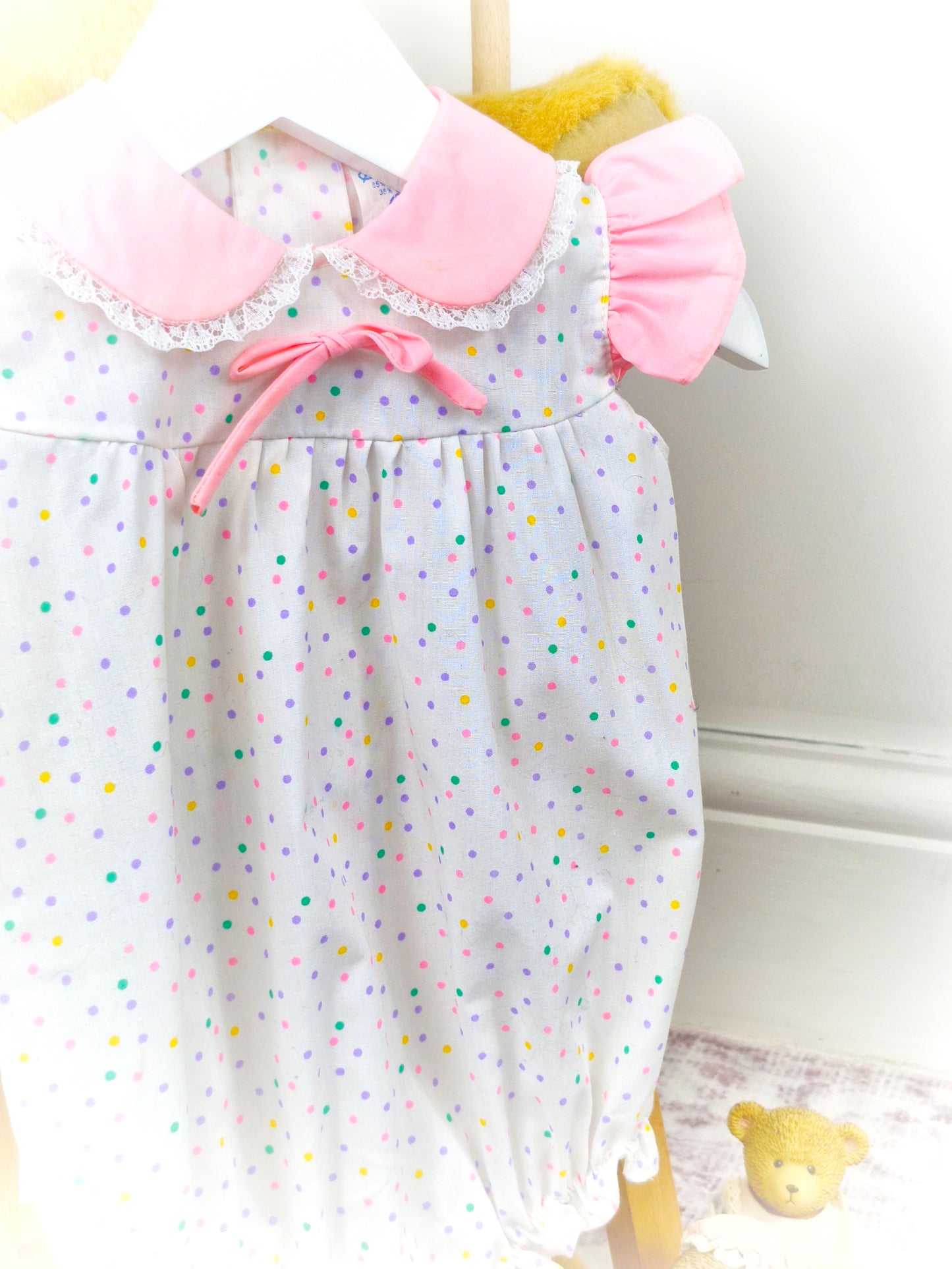 9-12 months. White vintage romper with pink collar, flutter shoulders and rainbow polka dots