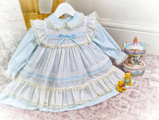 12-18 months. Light blue vintage dress from Toddle Tyke with white apron, satin ribbon, lace and frills