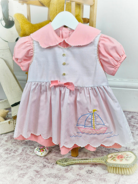 12-18 months. Pink vintage dress with puff sleeves and collar, white apron with scalloped hem and embroidered ship