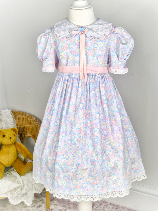 5-6 years. Pastel floral vintage Bryan with puff sleeves, pink waist tie and ribbon bow.