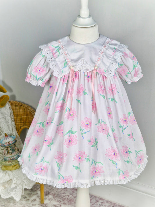 3 years. White vintage dress from Mini Togs with pink floral print, white bib with eyelet trim and pink satin ribbon