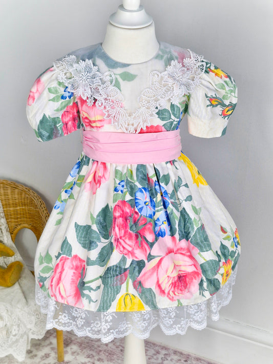 4 years. Vintage Jinelle dress with vibrant floral print, white lace bib collar and pink waist tie and lace hem