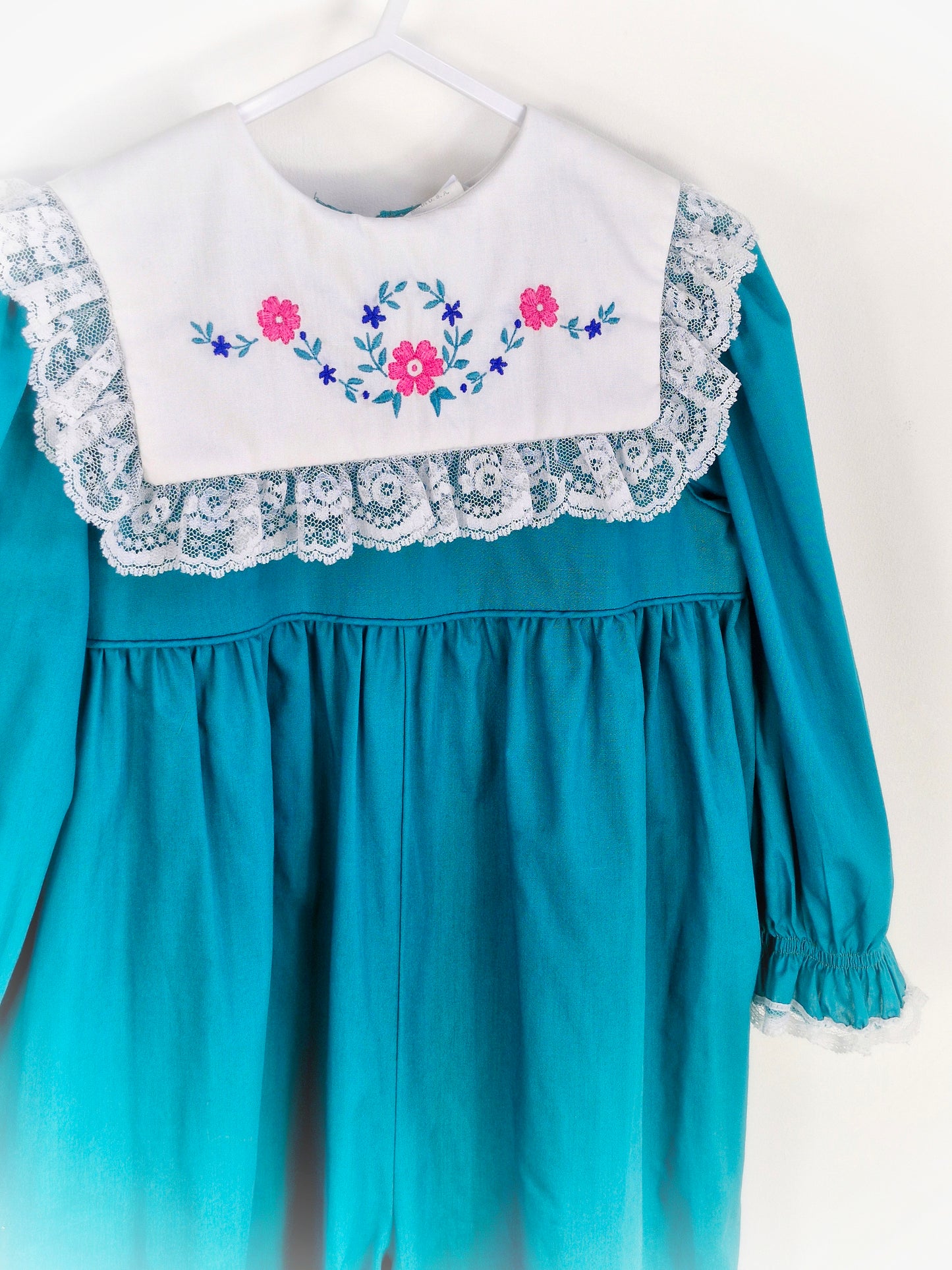 3 years. Teal vintage romper from Bryan with white bib, embroidered with flowers and trimmed with lace, cuffed wrists and ankles