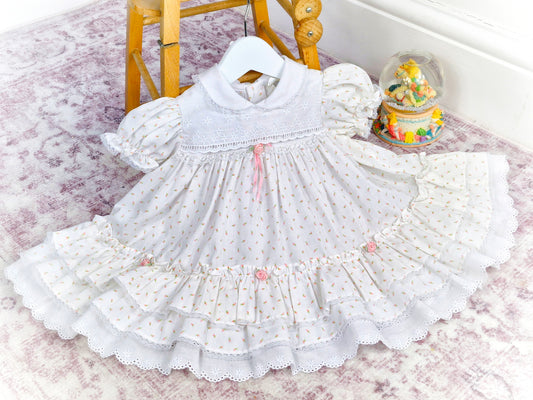 12-18 months. White vintage dress with pink floral print, rosettes and ribbon, puff sleeves and embroidered chest
