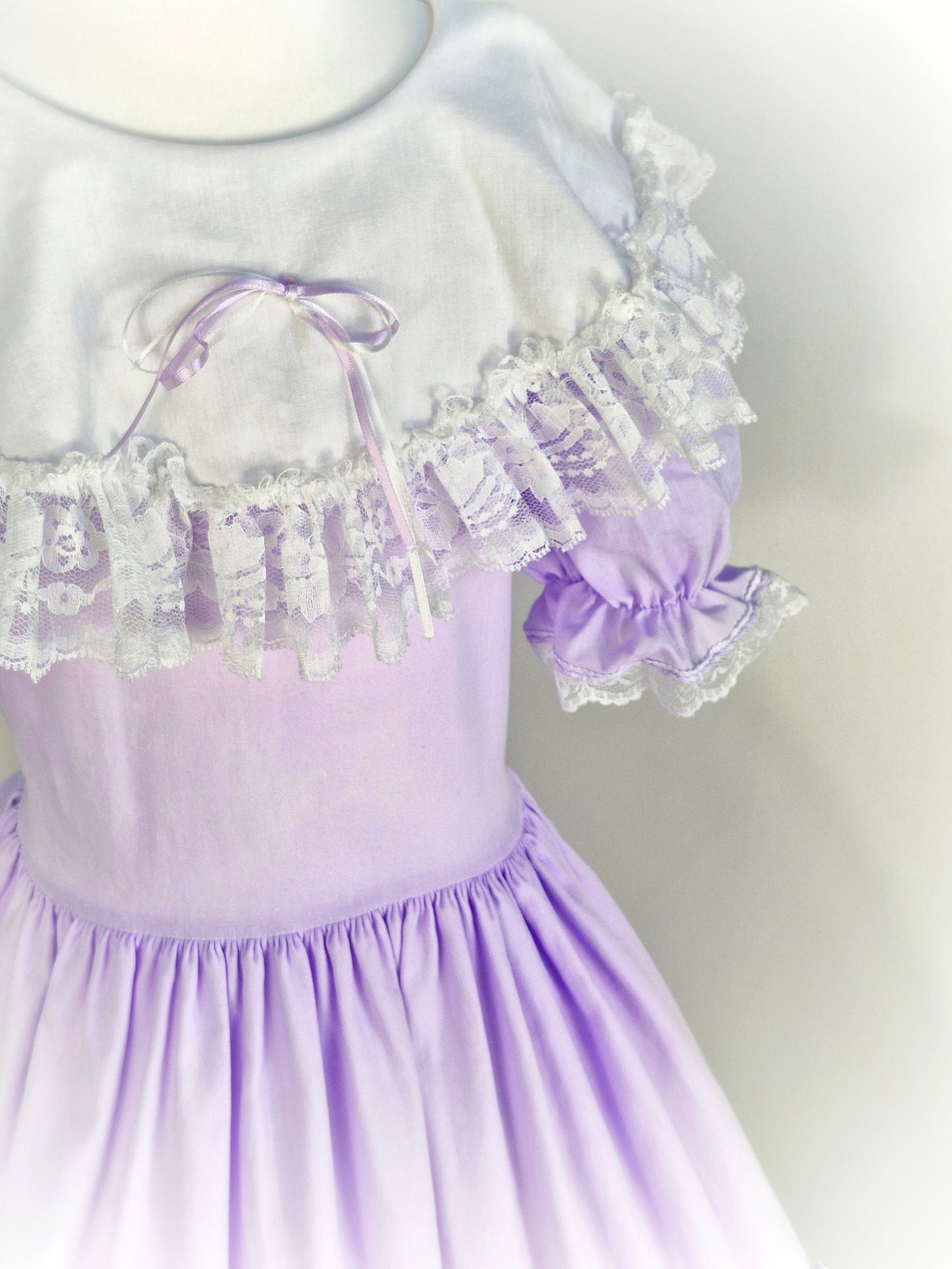 12-14 years. Lilac Lid'l Dolly with white bib, puff sleeves and lace trim