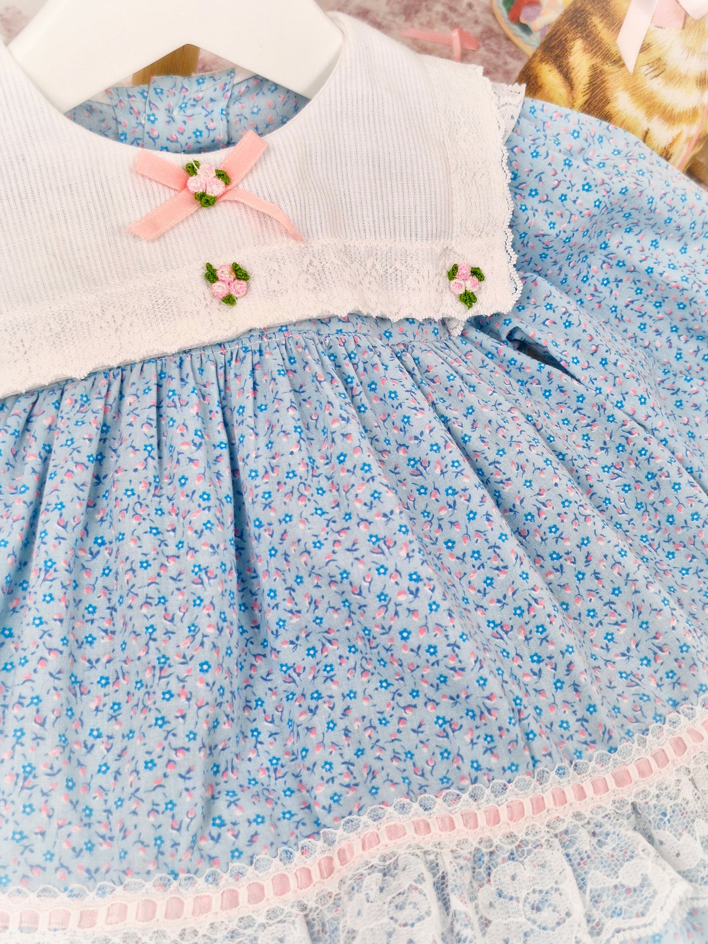 9-12 months. Blue floral vintage dress with white bib and lace, pink satin ribbon and rosettes