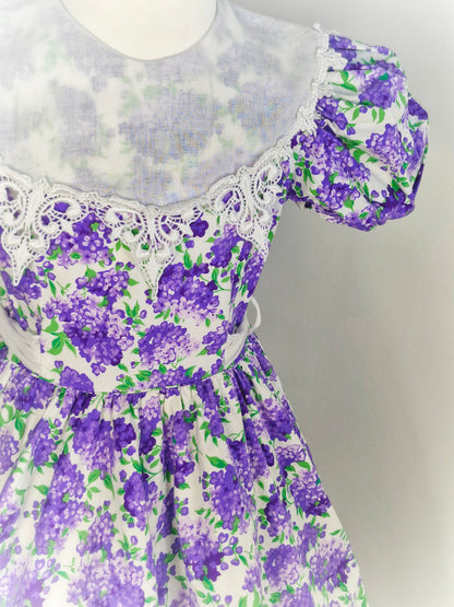 7-8 years. White vintage dress from Jayne Copeland with purple and green floral design, large white bib and puff sleeves