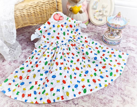 18 months. White sleeveless vintage dress with primary coloured bows and buttons print