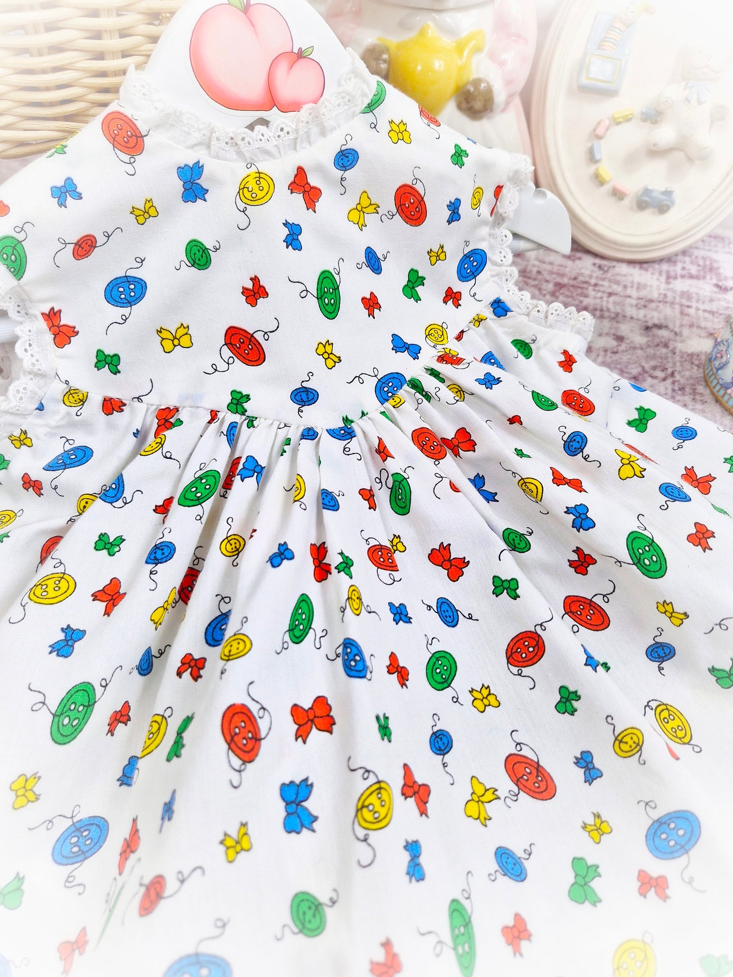 18 months. White sleeveless vintage dress with primary coloured bows and buttons print