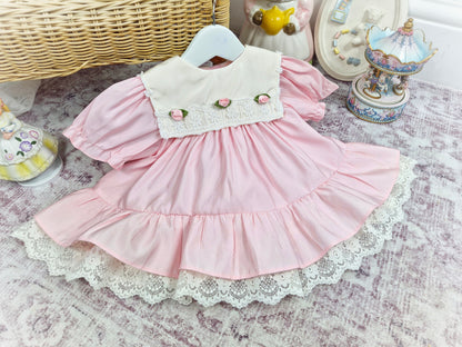 12-18 months. Pink vintage Bryan dress with white bib, lace hem and 3 rosettes