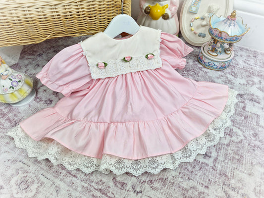 12-18 months. Pink vintage Bryan dress with white bib, lace hem and 3 rosettes