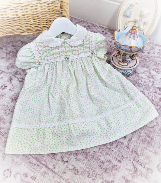 12-18 months. Cream vintage Polly Flinders dress with green and pink print, smocking with pink embroidered flowers and white collar