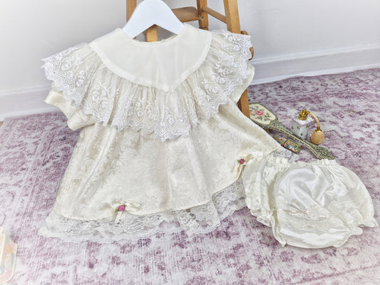 18-24 months/ 2 years. Cream vintage Bijan Kids with lace bib and hem, dusky pink rosettes and matching bloomers