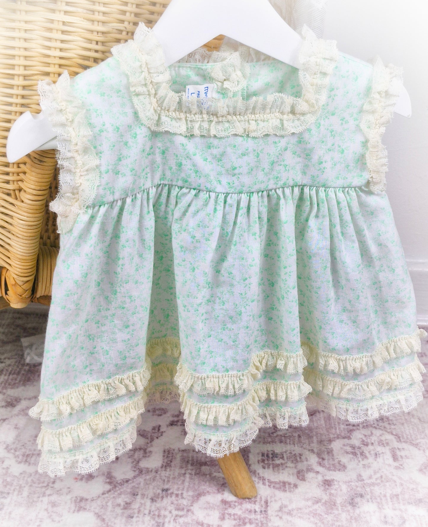 6-9 months. Vintage sleeveless Miniworld dress with green floral patterns and cream coloured lace