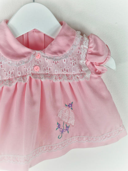 0-3 months. Pink vintage dress with eyelet lace details, puff sleeves and embroidered umbrella