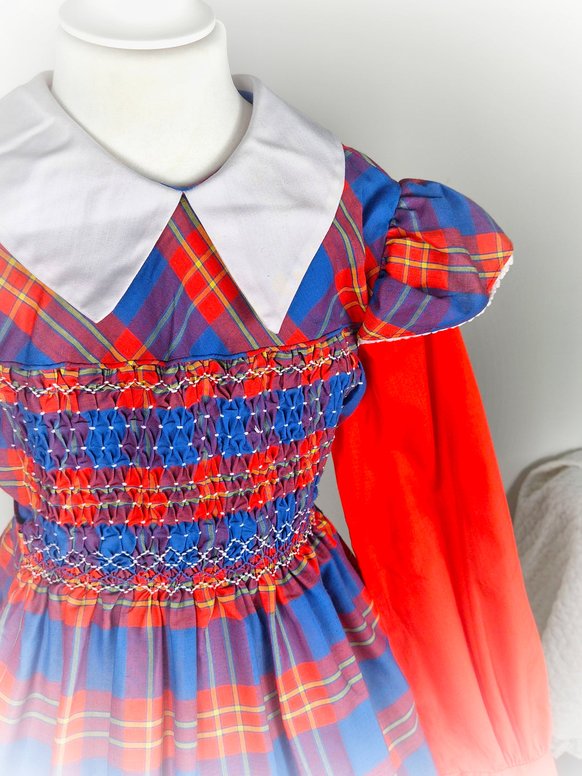 9-10 years. Red and blue tartan smock dress by Polly Flinders with white collar and flutter shoulders