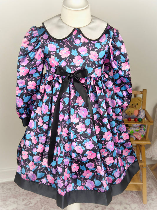 5 years. Black satin vintage dress by Charlianne with pink and blue floral patterns, white collar and black bow