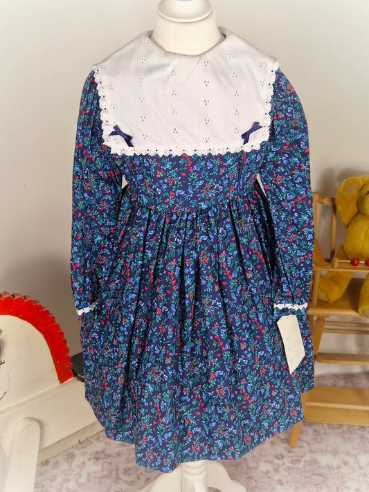 7-8 years. Navy floral vintage dress with long sleeves, white eyelet bib and satin bows. Deadstock