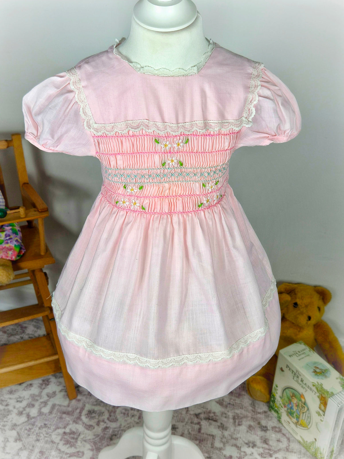 3 years. Pink vintage smock dress from Polly Flinders with white lace trimmed bib and embroidered flowers
