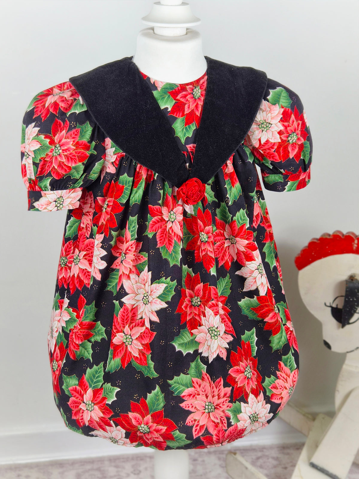 3 years. Black vintage dress with red poinsettia and green leaf festive print, black velour collar and red floral centre