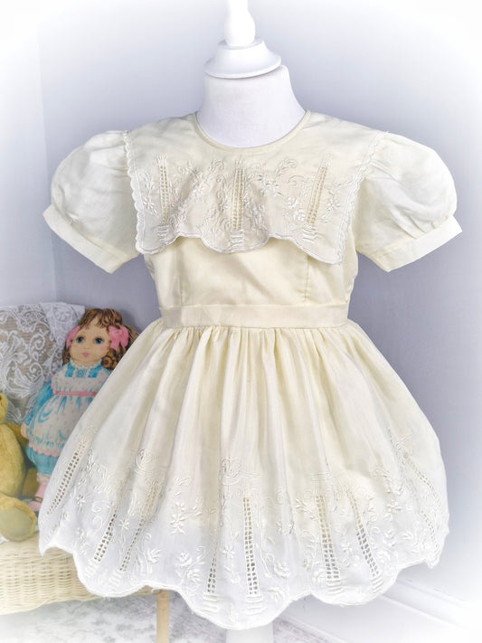 3 years. Cream vintage dress, puff sleeves, scalloped bib and hem with embroidered floral patterns