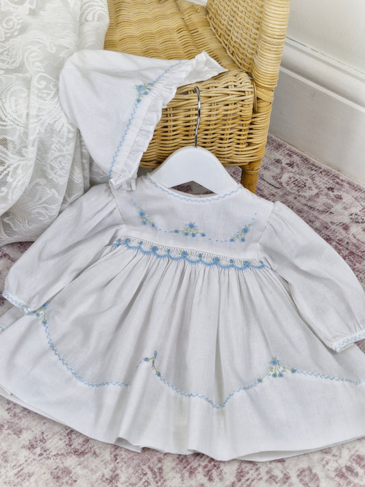 9 months. Sarah Louise dress and bonnet set, white with blue smocking and embroidered flowers