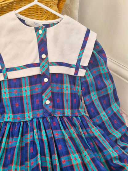 7-8 years. Vintage plaid patterned dress with large white bib, long sleeves and button down front