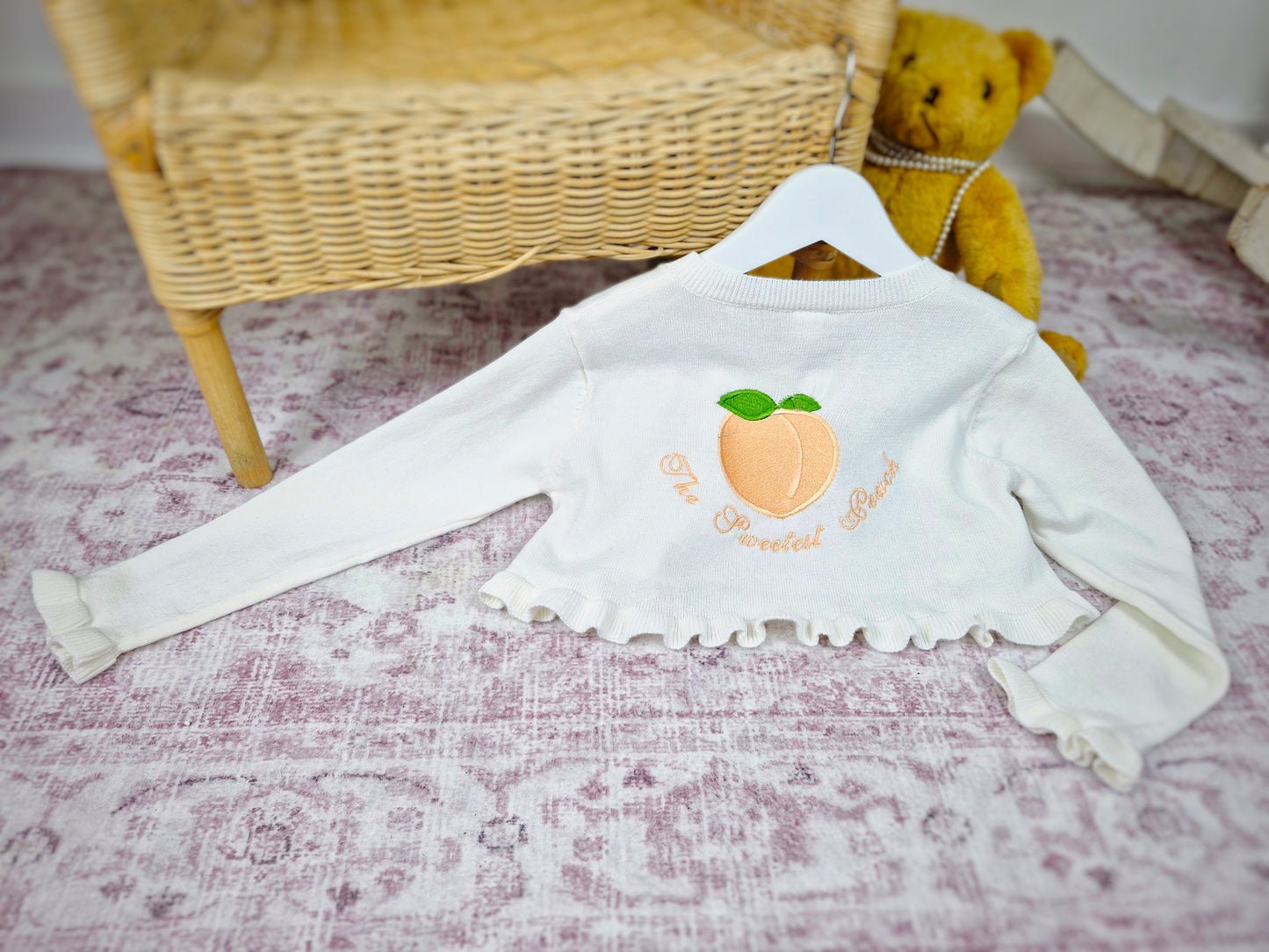 Frilly cream knit bolero with The Sweetest Peach embroidered on the back
