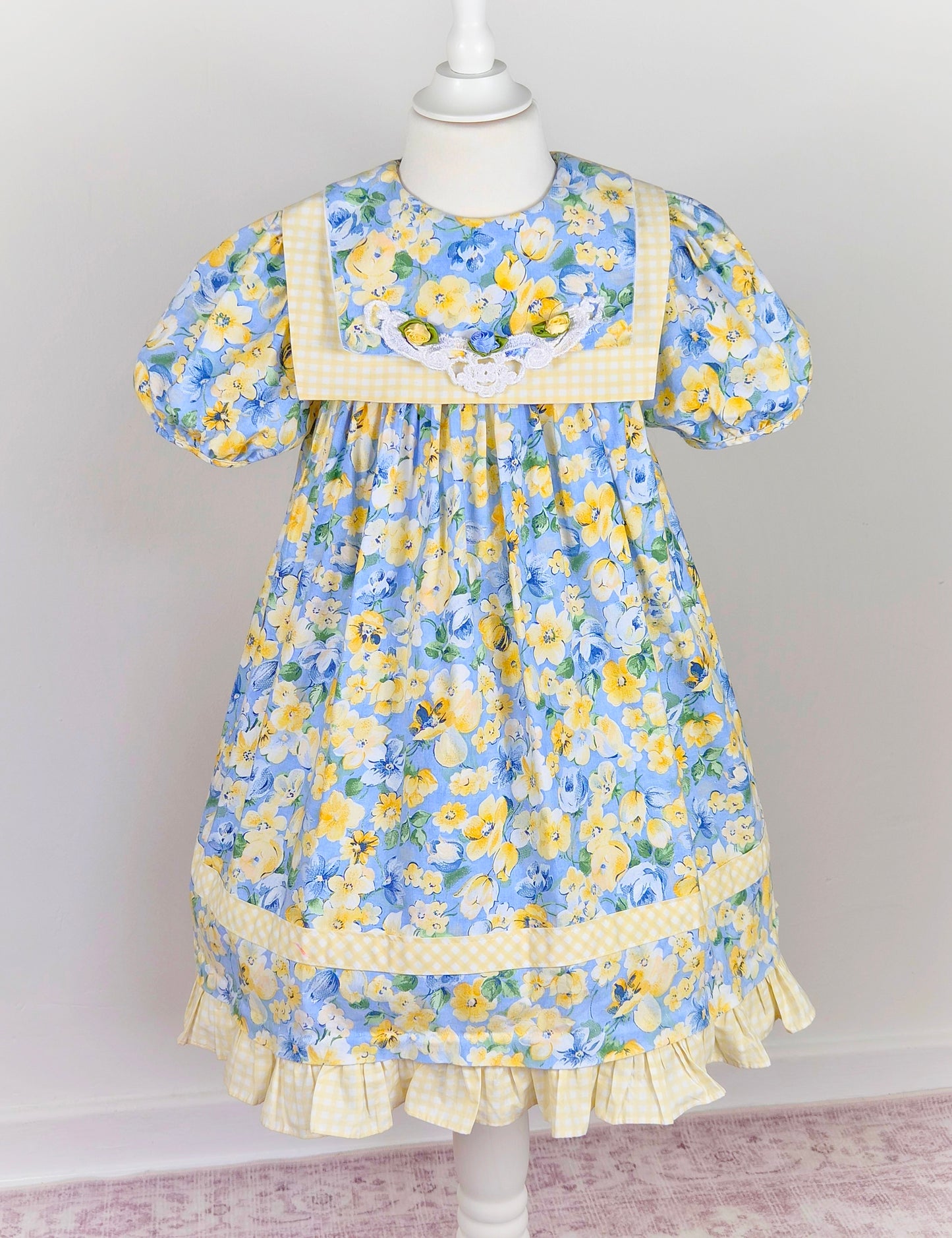 6-7 years. Blue and lemon floral vintage dress from Rare Editions with lemon and white gingham trim and three rosettes