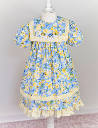 6-7 years. Blue and lemon floral vintage dress from Rare Editions with lemon and white gingham trim and three rosettes