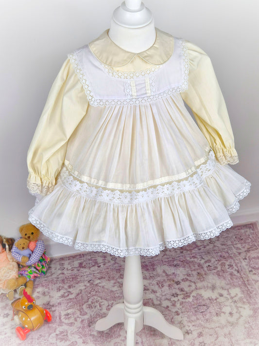 2 years. Two piece vintage Bryan set, creamy lemon long sleeve dress with white pinny trimmed with lace and ribbon