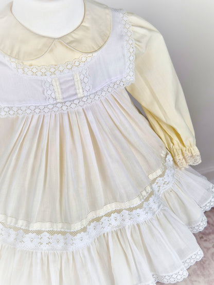 2 years. Two piece vintage Bryan set, creamy lemon long sleeve dress with white pinny trimmed with lace and ribbon