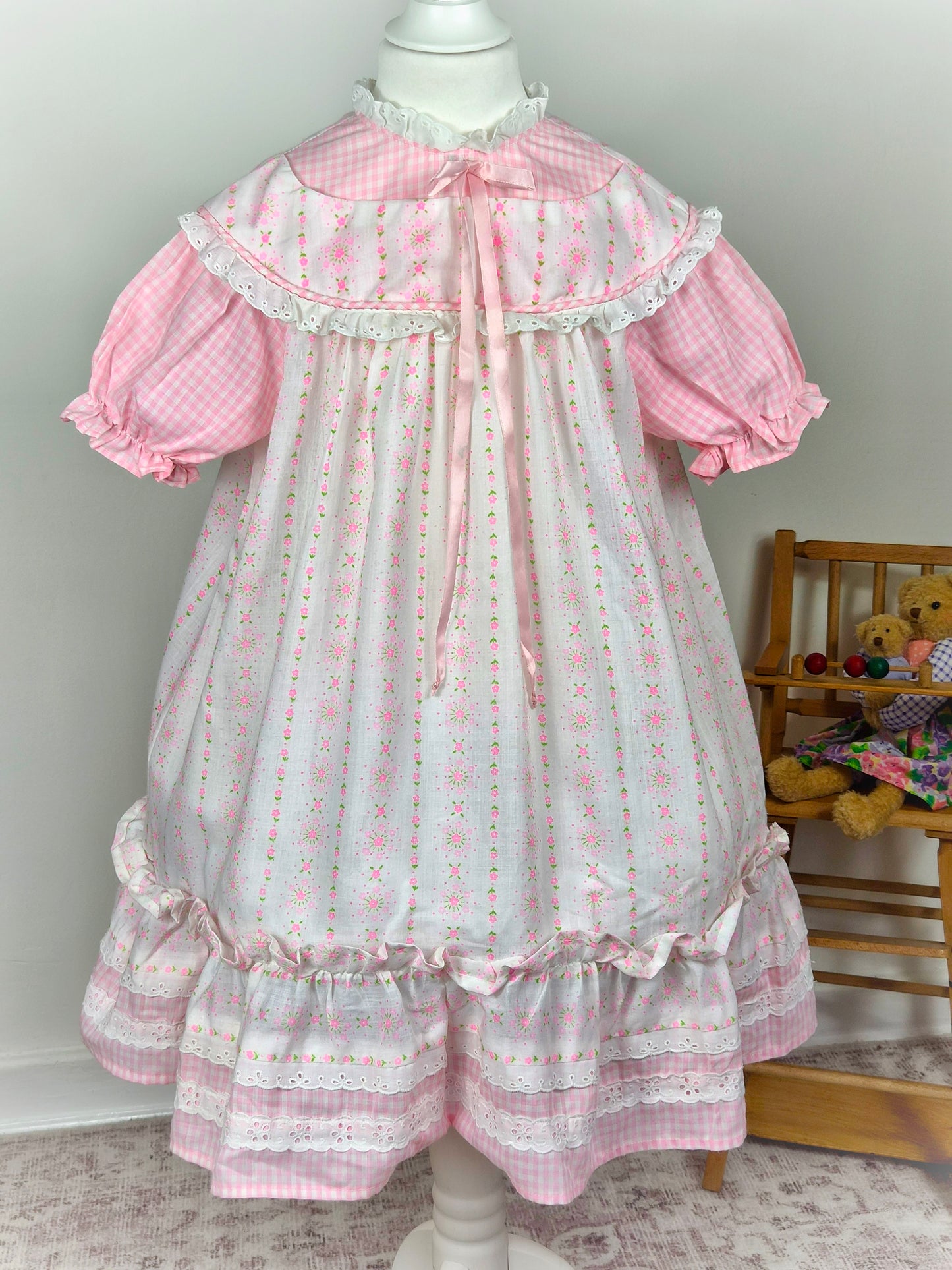 6-7 years. Pink and white gingham dress with floral patterns, pink satin ribbon and puff sleeves