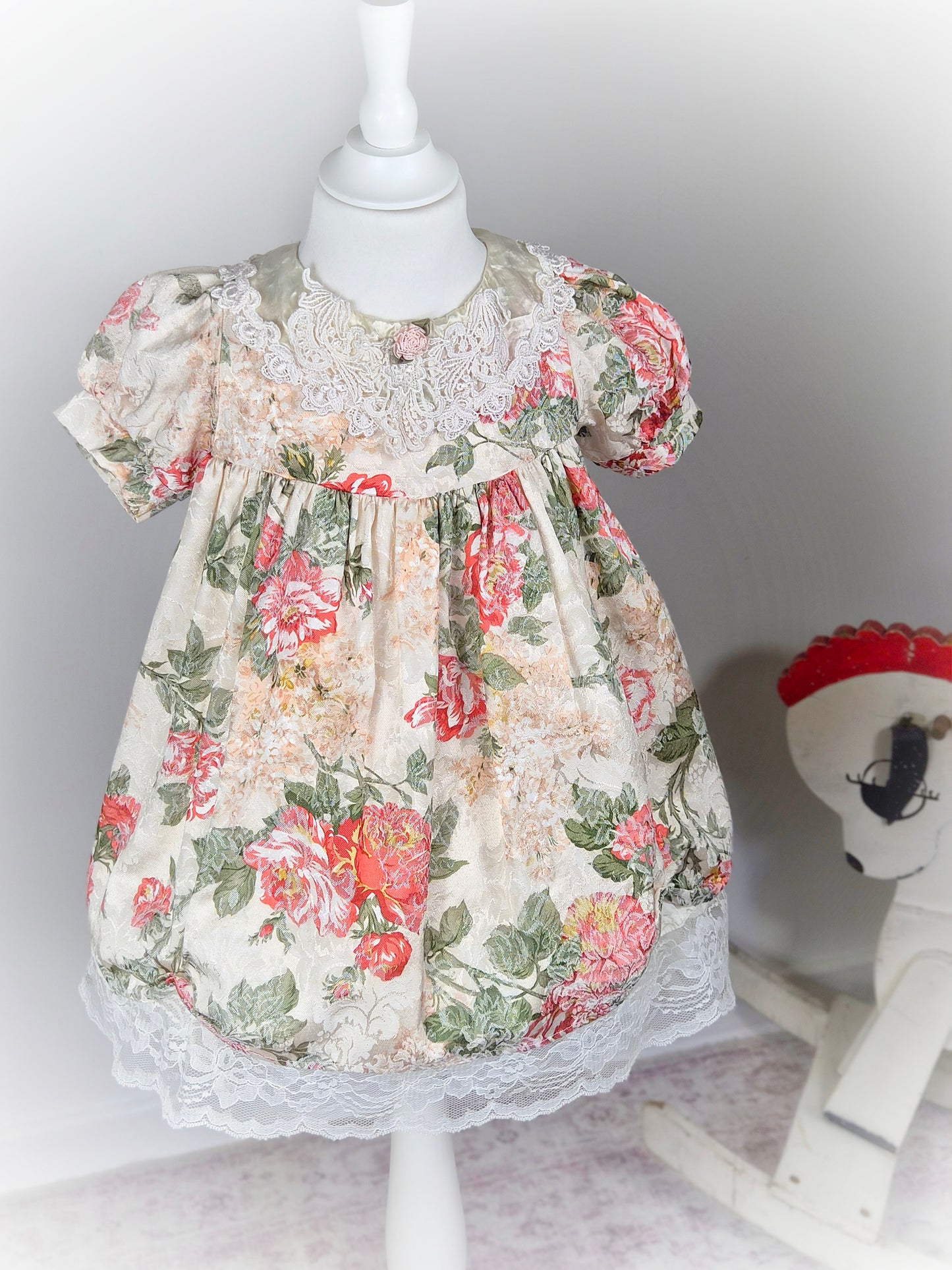 3 years. Cream vintage floral dress with puff sleeves, satin and lace bib and pink rosette